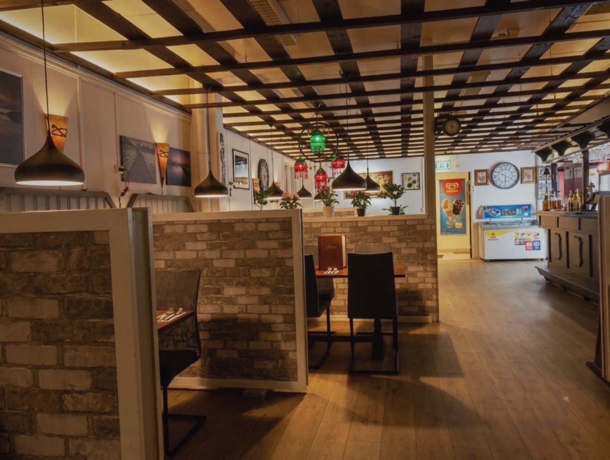 Innsiden av restauranten med båser, teglvegger og varme lamper